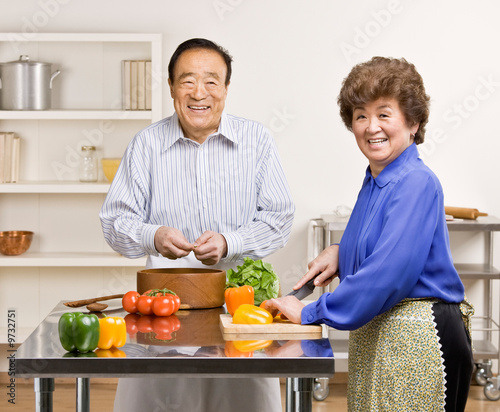 Photo: Man preparing wholesome salad with wife in kitchen for dinner Man preparing wholesome salad with wife in kitchen for dinner