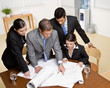Architect explains problem on blueprint to co-workers