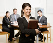 Confident businesswoman with notebook and co-workers