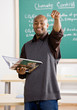 Teacher holding text book pointing to student in classroom