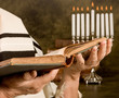 Hands holding a jewish prayer book wearing a prayer shawl