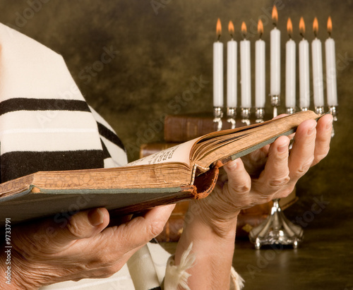 Hands holding a jewish prayer book wearing a prayer shawl