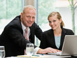 Businessman and female co-workers posing with laptop