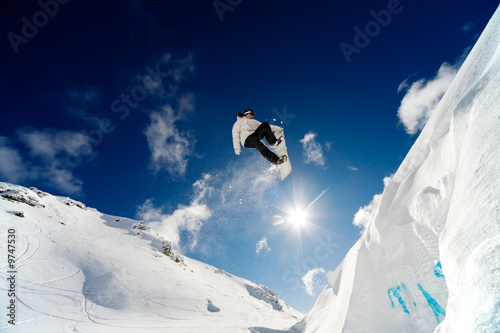 Photo: Snowboarder jumping through the air with blue sky background Snowboarder jumping through the air with blue sky background
