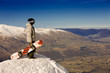 A snowboarder stands on a peak over looking a spectacular view