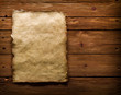 An ancient paper with torn edges, on a brown wooden surface.