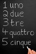 A teacher writing numbers one to five in the Italian language.