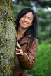 Freundlicher Teenager sieht hinter einem Baum hervor