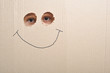 Eyes looking through two holes on a cardboard and a smile Eyes looking through two holes on a cardboard and a smile