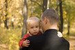 Young man takes his crying sun in his arm in autumn park Young man takes his crying sun in his arm in autumn park
