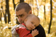 Young man takes his little son in his arms in autumn park Young man takes his little son in his arms in autumn park
