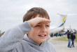 Boy peering with palm near brow against airplane Boy peering with palm near brow against airplane