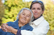 Middleaged woman cuddles her elderly mother
