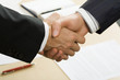 Photo of business handshake over workplace Photo of business handshake over workplace