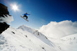 Snowboarder jumping through air from rock drop