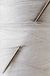 Photo: closeup of a needle stuck in a spool of white thread closeup of a needle stuck in a spool of white thread