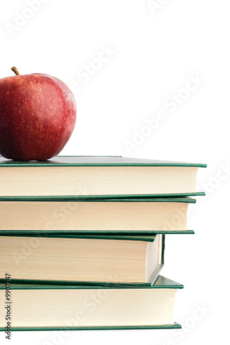 Photo: A red apple on top of many books on a white background A red apple on top of many books on a white background