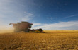 A combine havester working with debri and dust flying