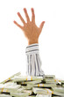 Close-up of man’s hand protruding from heap of dollar bills