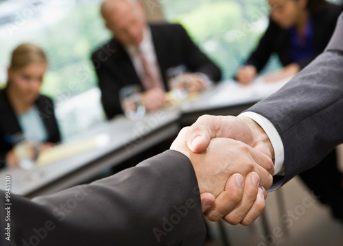 Photo: Close up of businessmen shaking hands in conference room Close up of businessmen shaking hands in conference room