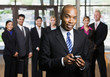 African businessman using cell phone in front of co-workers