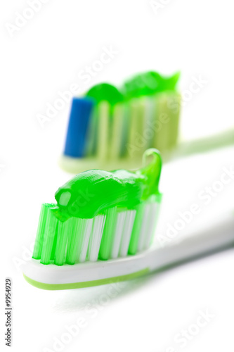 Photo: two toothbrushes with green toothpaste isolated two toothbrushes with green toothpaste isolated