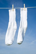 A pair of white socks on a clothesline in front of a blue sky