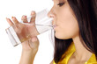 Beautiful young girl drinks water from glass isolated