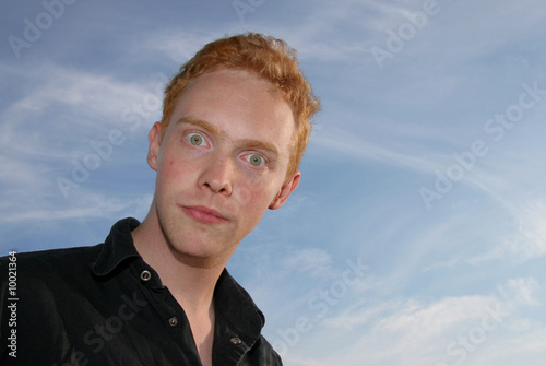 Photo: Wide-eyed young man against blue sky Wide-eyed young man against blue sky