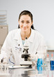 Scientist in lab coat and rubber gloves looking at specimen