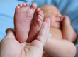Hand holding newborn baby feet