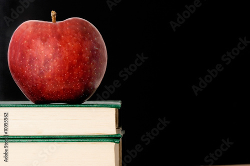 Photo: A red apple red on a green book on a black background A red apple red on a green book on a black background