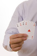A busiines man holding four playing cards with aces