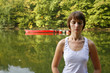 Woman doing yoga on lake in park in autumn