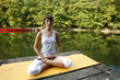 Woman doing yoga on lake in park in autumn
