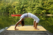 Woman doing yoga on lake in park in autumn