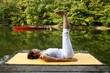 Woman doing yoga on lake in park in autumn
