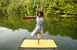 Woman doing yoga on lake in park in autumn