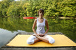 Woman doing yoga on lake in park in autumn