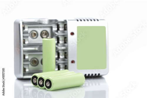 Batteries and charger reflected on white background. Shallow DOF