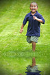 Happy mixed race boy running through green grass
