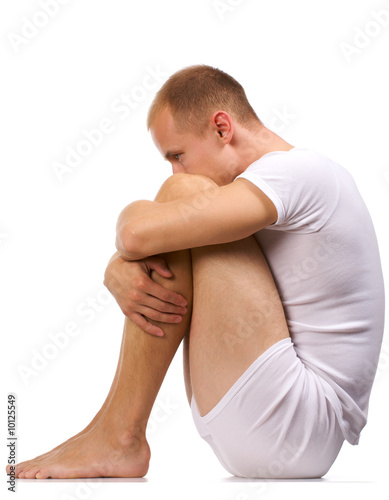 Photo: Melancholy young man in white. To sit having clasped knees. Melancholy young man in white. To sit having clasped knees.
