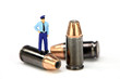 Miniature police officer standing on a bullet. Law enforcement.