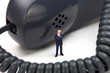 Miniature businessman stands in front of a phone receiver. Miniature businessman stands in front of a phone receiver.