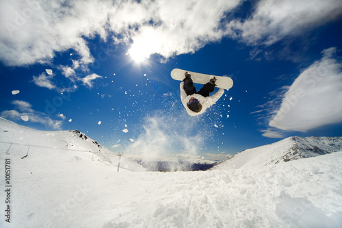 Photo: Snowboarder going off jump doing a backflip Snowboarder going off jump doing a backflip