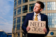 Crisis. Young businessman holding sign Need Job