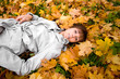Young woman laying on a autumn leaves. Focus on the face.