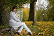 Young woman sits in autumn park. Focus on the face.