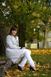 Young woman sits in the autumn park. Focus on the face.