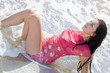 The beautiful young woman lies in waves on sea coast